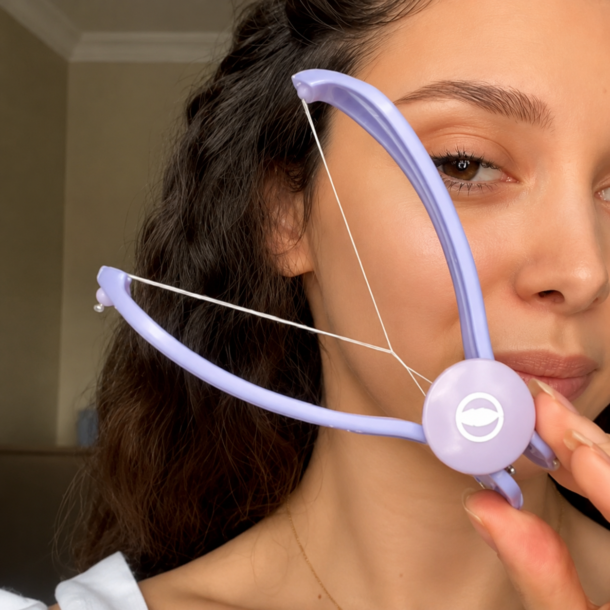 Woman using Threadle brow threading tool at home
